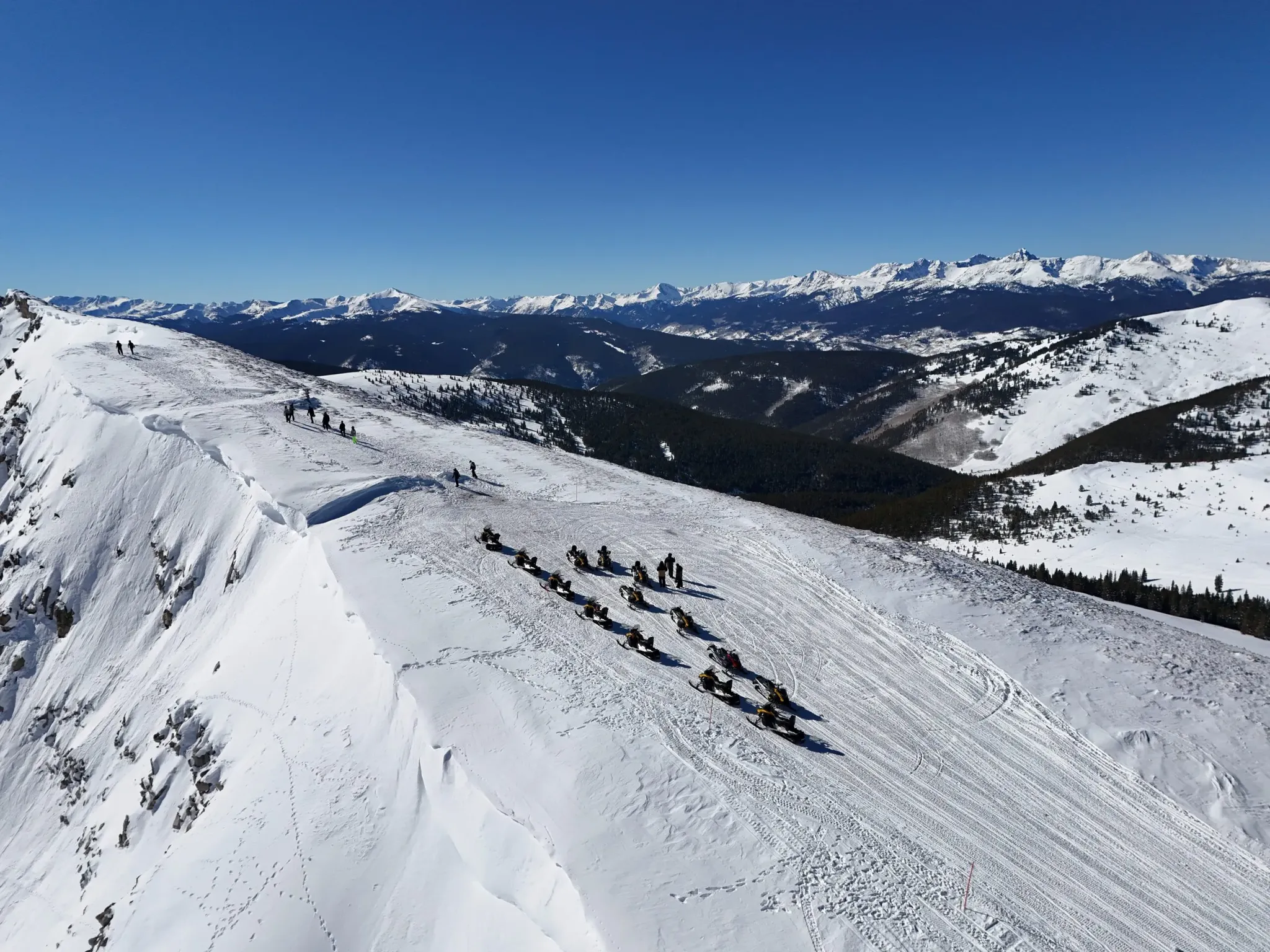 Snowmobile riders on a guided tour near Denver, Colorado with Rocky Mountain views.